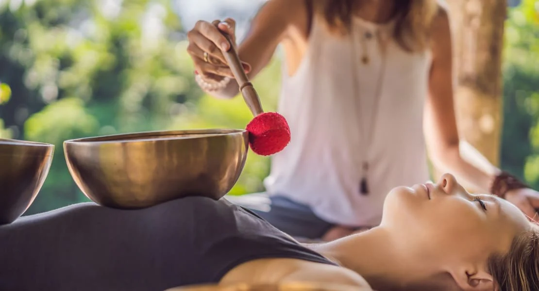 Une-femme-effectuant-un-massage-sonore-avec-des-Bols-Tibetains
